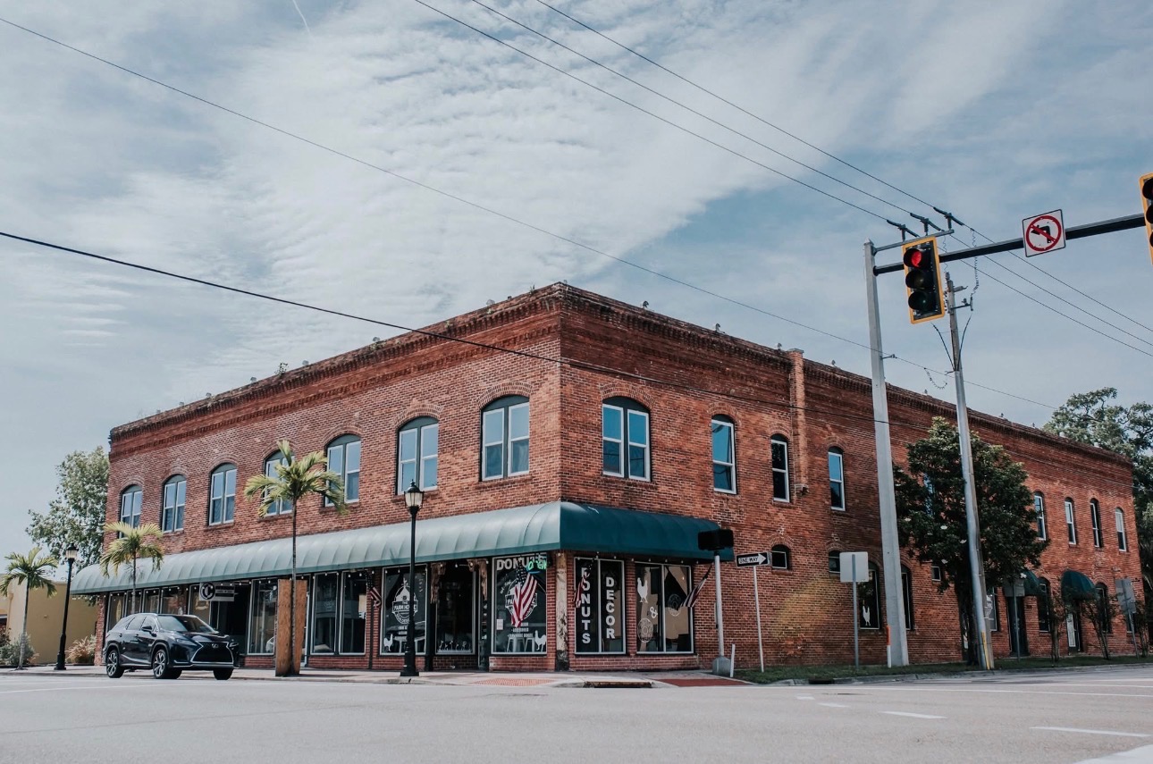 The Urban Market Co. building — a two-story red brick storefront with a dark green awning on a Bradenton street corner